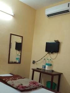 Habitación con cama, espejo y TV. en Narendra niketan en Calcuta