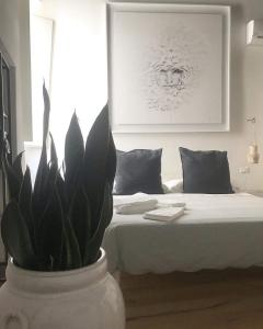 Un jarrón blanco con una planta delante de una cama. en Orazio33 b&b, en Monopoli