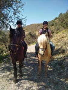 dos personas montando caballos en un camino de tierra en La Ferme des Cailletiers chez Marco, en Lucéram