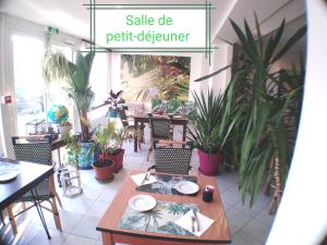 a table and chairs in a restaurant with plants at Le vent des globes in Les Sables-dʼOlonne