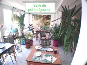 een tafel en stoelen in een restaurant met planten bij Le vent des globes in Les Sables-dʼOlonne