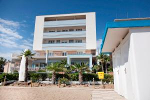 a white building with palm trees in front of it at Hotel Elios in Bellaria-Igea Marina