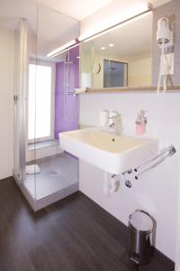 uma casa de banho com um lavatório branco e um chuveiro em Hotel Restaurant Resslirytti em Basileia