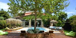 a backyard with a swimming pool and a tree at Turdus Merula Retreat in Nea Makri
