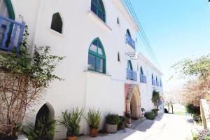 a white building with blue windows and potted plants at Axiothea Hotel in Paphos City