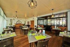 a dining room with tables and chairs in a restaurant at Les Cols Verts - Logis Hôtels in La Tranche-sur-Mer
