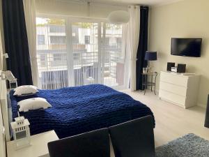 a bedroom with a blue bed and a balcony at Apartament Nautica Pogorzelica in Pogorzelica