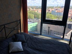 a bed in a bedroom with a view of a city at City Apartment in Klaipėda