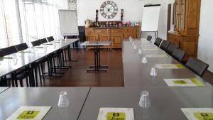 a conference room with tables and chairs and a clock at Les Cols Verts - Logis Hôtels in La Tranche-sur-Mer