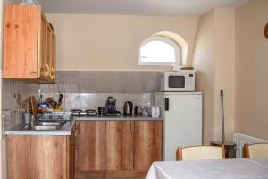 a kitchen with wooden cabinets and a white refrigerator at Ambrózia Guesthouse in Nagykanizsa