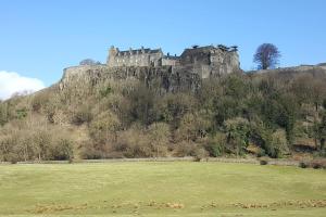 un castillo en la cima de una colina con un campo en Thornhill House - Historic 5 Bedroom 5 Ensuite, en Stirling
