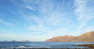 a view of the ocean with mountains in the background at El Charquito in Famara