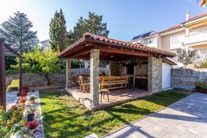 un gazebo in legno con panchina in cortile di Apartmani Velnic a Baška