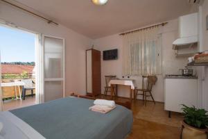 a bedroom with a bed and a kitchen with a table at Studios Bačić in Vela Luka
