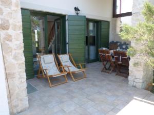 a patio with rocking chairs and a table at Studio apartman - MELLITUS in Molat