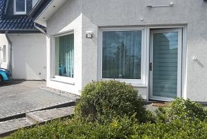 una casa bianca con una porta e alcuni cespugli di Helles 1-Zimmer-Apartment in Hemmingen/Hannover a Hemmingen