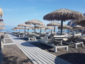 een rij stoelen en rieten parasols op een strand bij Ocean View in Kamari