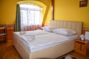 un letto con lenzuola e cuscini bianchi in una camera da letto di Ambrózia Guesthouse a Nagykanizsa