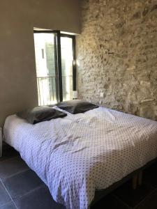 a bed in a room with a stone wall at 13 QUAI JEAN JAURES in LʼIsle-sur-la-Sorgue