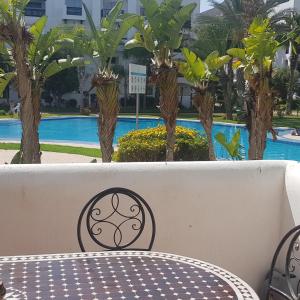 a bench with a table and palm trees in the background at Luxury Flat Marina Agadir in Agadir