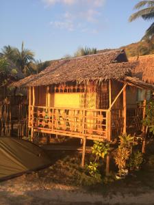 a house with a straw roof and a tent at Seafront Cottage Ocam Ocam Beach in Busuanga