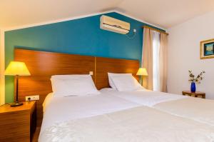 Un dormitorio con una gran cama blanca con una pared azul. en Pansion Srebreno, en Mlini