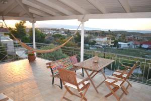 a patio with a hammock and a table and chairs at Corinthian Sun - Vacation Home in Korinthos