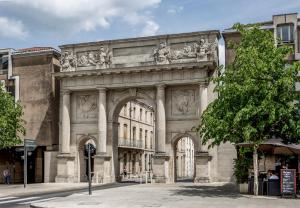 a large stone building with an arch in a street at Mercure Nancy Centre Gare in Nancy