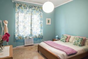 um quarto com paredes azuis, uma cama e uma janela em La Casa di Giò em Asti