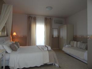 a bedroom with a large white bed and a couch at Palmina Mare in Paralia Vrachou