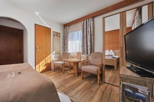 um quarto de hotel com uma cama, uma televisão e uma mesa em Breitenhof - Haus Breiten em Angath