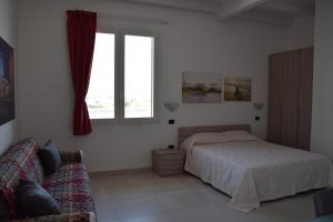 una camera con letto, finestra e divano di Appartamento Flora a Gallipoli