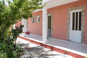 
a white building with a red door and a tree at MARO STUDIO & APARTMENTS in Arillas
