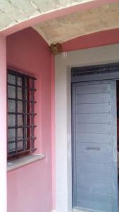 różowy dom z drzwiami i oknem w obiekcie La Corte di Nonno w mieście Frascati