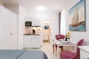 Dieses weiße Zimmer verfügt über ein Bett, einen Tisch und eine Küche. in der Unterkunft Apartman Arbol in Split