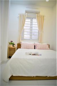 Un dormitorio con una gran cama blanca con ventana. en H Best Hostel Cafe SaiGon, en Ho Chi Minh