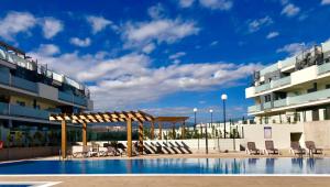 a swimming pool with chairs and a pavilion next to a building at El Medano, La Tejita in El Médano