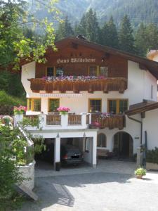 ein Gebäude mit einem Balkon mit Blumen darauf in der Unterkunft Haus Wildebene in Sankt Anton am Arlberg