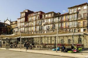 un edificio con gente sentada en mesas delante de él en YOUROPO - Ribeira Porto, en Oporto