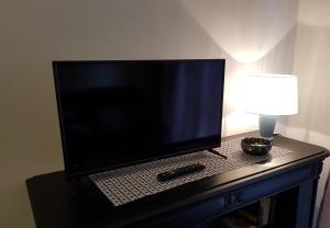 a flat screen tv sitting on a table with a lamp at L'airone apartment in Casale Monferrato
