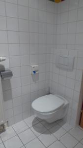 a white toilet in a white tiled bathroom at Thermen Chalet 85m² in Lutzmannsburg