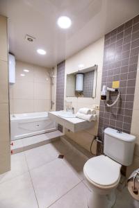 a bathroom with a toilet and a sink and a tub at Kolkhida Resort & Spa in Ureki
