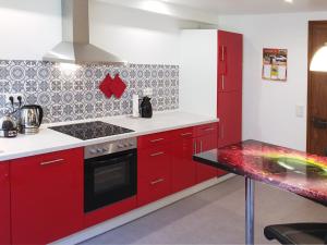 a kitchen with red cabinets and a stove top oven at Le Chamois in Sondernach