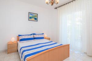 een witte slaapkamer met een bed en een raam bij FBA Family Beach Apartments in Omiš