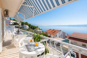 een balkon met tafels en stoelen en uitzicht op het water bij FBA Family Beach Apartments in Omiš