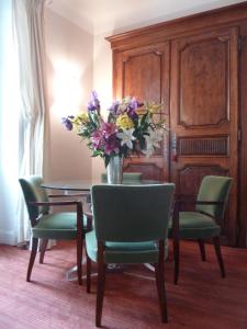 un comedor con una mesa con un jarrón de flores en Hôtel Maïtagaria, en Biarritz