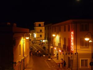 une rue de la ville la nuit avec des gens qui marchent dans la rue dans l'établissement Albergo Residenziale La Corte, à Tortolì