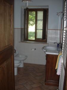 Un baño con lavabo, inodoro y ventana. en Agriturismo Il Pratone, en Castiglione dʼOrcia