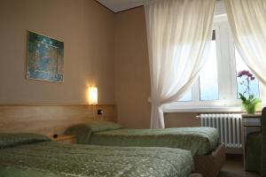 a hotel room with two beds and a window at Hotel Milano in Folgaria
