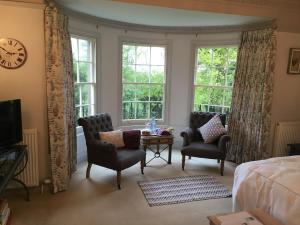 a bedroom with two chairs and a table and windows at Buckton Farmhouse in Belford